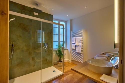 y baño con bañera y ducha acristalada. en Appartement Montagnon - les suites du palais - Classé 4 étoiles, parking privé, vue cathédrale, 3 chambres, PRIMO C0NCIERGERIE, en Nevers