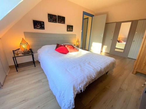 Un dormitorio con una cama blanca con almohadas rojas. en Maison Pleuven, 7 pièces, 7 personnes - FR-1-481-99 en Pleuven