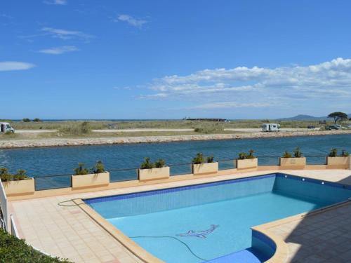 - une piscine à côté d'un corps d'eau dans l'établissement Studio Cabine avec Piscine, Terrasse, Parking et Proche Plage à Saint-Cyprien - FR-1-225D-127, à Saint-Cyprien