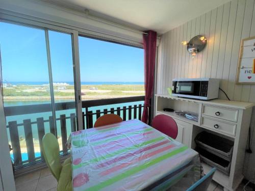 Cette chambre comprend une table avec des chaises et un four micro-ondes. dans l'établissement Studio Cabine avec Piscine, Terrasse, Parking et Proche Plage à Saint-Cyprien - FR-1-225D-127, à Saint-Cyprien