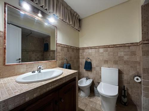 Un baño con lavabo, inodoro y espejo. en Perla 5, primera línea de playa y centrico, en Fuengirola