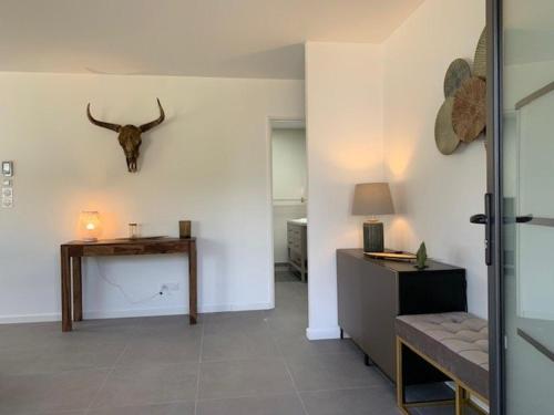 a living room with a table and a bull skull on the wall at Maison 3* à Trébeurden: jardin clos, 2 chambres, proche plage et sentiers - FR-1-542-46 in Trébeurden