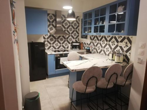 eine Küche mit blauen Schränken und einer Theke mit Stühlen in der Unterkunft Svolio Welcome in Thessaloniki