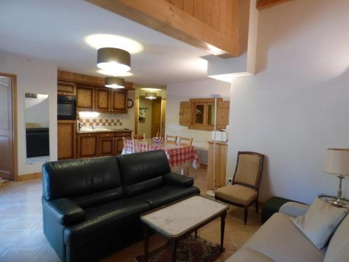 Il comprend un salon avec un canapé en cuir noir et une cuisine. dans l'établissement Magnifique T2 58m², centre Chinaillon, proche pistes, balcon ouest, parking, 3 étoiles - FR-1-458-156, au Grand-Bornand