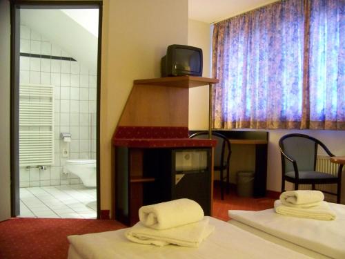 a room with two beds and a bathroom with a tv at Hotel Amadeus ROYAL Berlin in Berlin