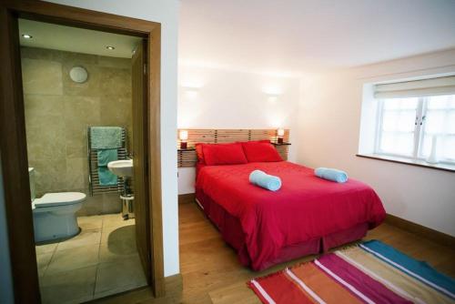 a bedroom with a red bed and a bathroom at Big Moo in Llanrhyddlad