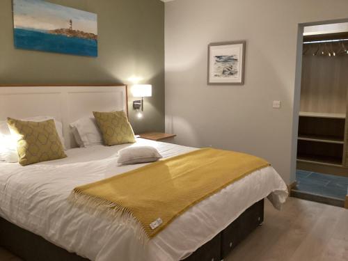 a bedroom with a large bed with a yellow blanket on it at Quayside luxury apt Roundstoneselfcatering in Roundstone