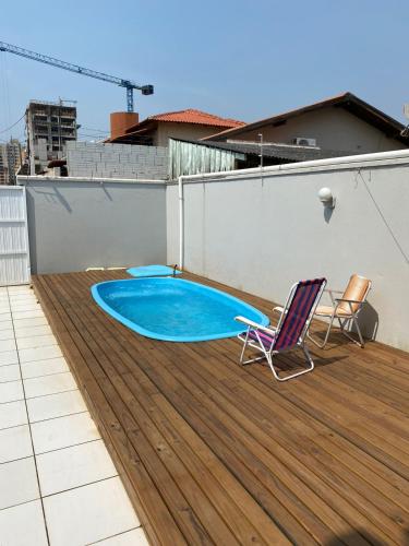 una terraza con piscina y 2 sillas en Casa de Hóspedes com Piscina em Porto Belo, en Porto Belo