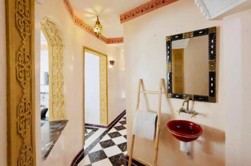 uma casa de banho com um lavatório vermelho e um espelho. em résidence qarya syahia private roof terrasse em Marraquexe