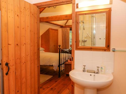 uma casa de banho com um lavatório, um espelho e uma cama em Stone Barn em Holsworthy
