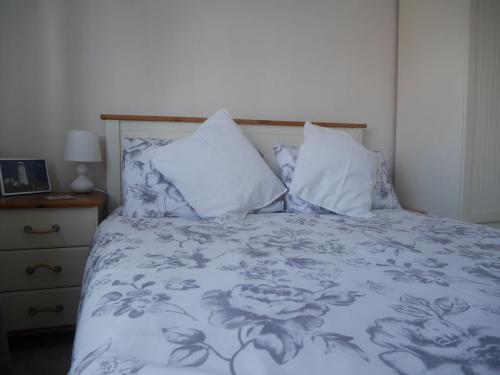 a bed with blue and white sheets and pillows at Cliffwalk Cottage in Portland