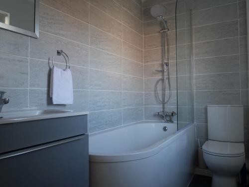 a bathroom with a tub and a toilet and a sink at Cliffwalk Cottage in Portland