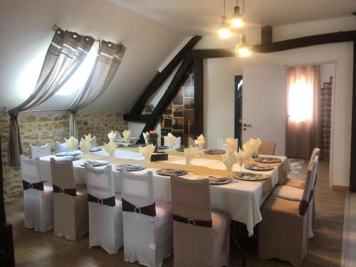 une salle à manger avec une grande table et des tables et des chaises blanches dans l'établissement VILLA REUNION FAMILIALE ET PROFESIONNALE, à Meunet-sur-Vatan