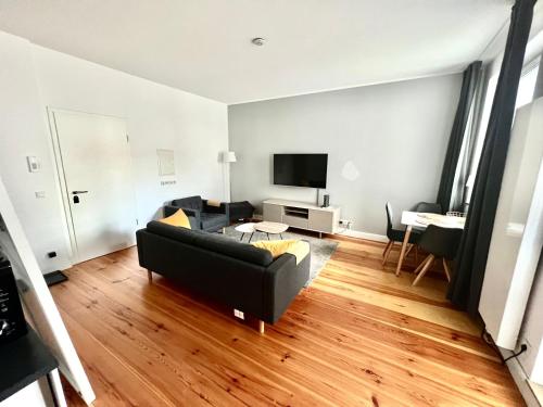 a living room with a black couch and a television at Vibehome Düsseldorf - Stresemannstraße in Düsseldorf