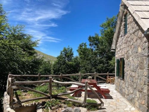 a stone building with a picnic table on a patio at Planinska kuća na Velebitu, s pogledom na more in Veliki Alan