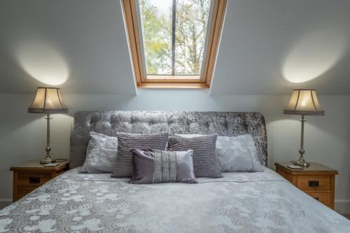 een slaapkamer met een bed met kussens en 2 lampen bij Maltings Lodge in Chelsworth