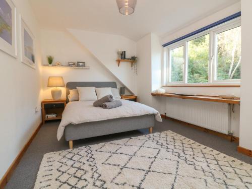 a bedroom with a bed and two windows and a rug at Hillsview in Ilfracombe