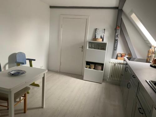 cocina blanca con mesa y puerta blanca en Casa Bianca, en Fehmarn