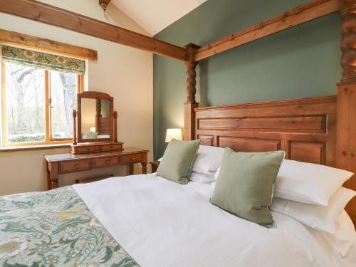 a bedroom with a white bed with a wooden headboard at Ash Cottage in Skipton