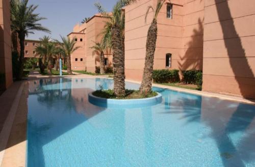 uma grande piscina azul com duas palmeiras em résidence qarya syahia private roof terrasse em Marraquexe