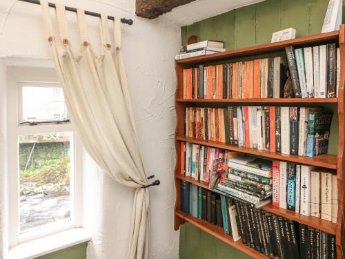 a book shelf filled with books next to a window at Pauls Fold Holiday Cottage in Ingleton