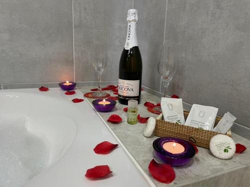 a bottle of wine and candles on a bathtub with roses at Apartamente Lux SYA Residence in Braşov