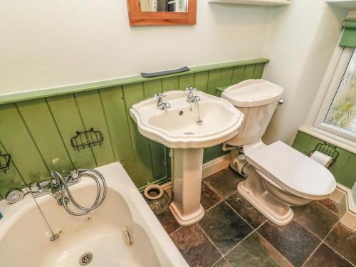 La salle de bains est pourvue d'un lavabo, de toilettes et d'une baignoire. dans l'établissement Pauls Fold Holiday Cottage, à Ingleton