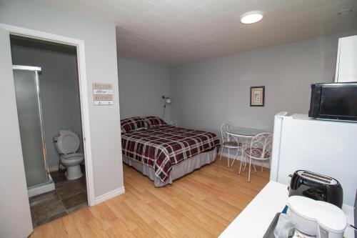 a bedroom with a bed and a table and a refrigerator at Motel de la mer in Rimouski