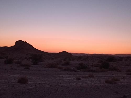 a sunset in the desert with a mountain in the background at אתיטיוד בערבה attitude at the arava in H̱aẕeva