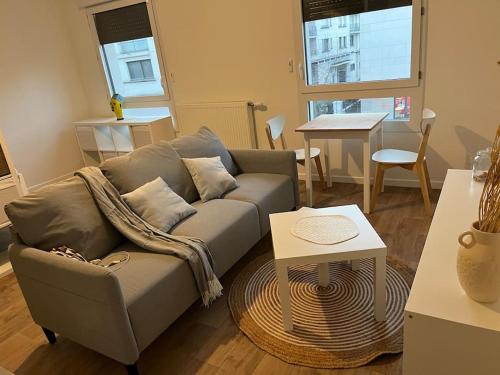 ein Wohnzimmer mit einem Sofa und einem Tisch in der Unterkunft Studio Cosy et Charmant au cœur de Saint Cyr in Saint-Cyr-lʼÉcole