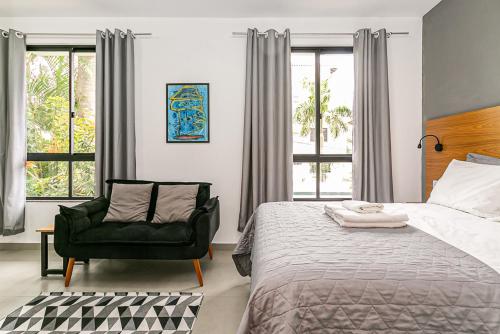 a bedroom with a bed and a chair and windows at Flats das Palmeiras in Florianópolis