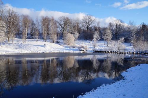 a snow covered field with a river and a bridge at Jaunkrastmaļi in Kandava