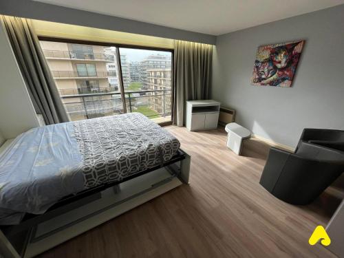 een slaapkamer met een bed en een groot raam bij Westhinder 605 in De Panne