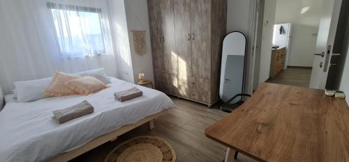 een slaapkamer met een bed en een houten tafel bij קסם של אירוח in Hagoshrim