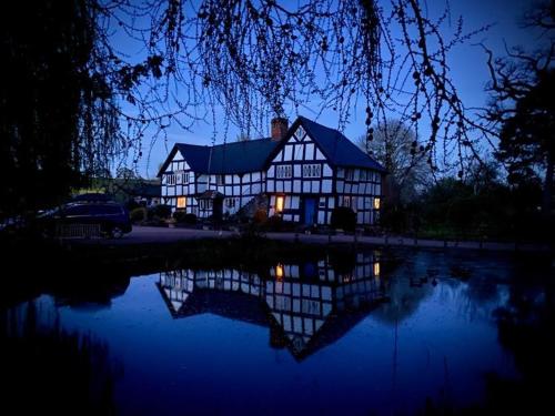 uma casa grande com o seu reflexo na água à noite em The Vauld, 2 bedroom suite with Bed and Breakfast em Bodenham