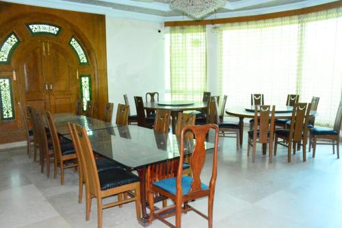 a dining room with tables and chairs and windows at Baani Signature in Islamabad