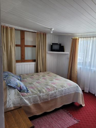 1 dormitorio con 1 cama y TV en Hospedaje Palena en Ancud