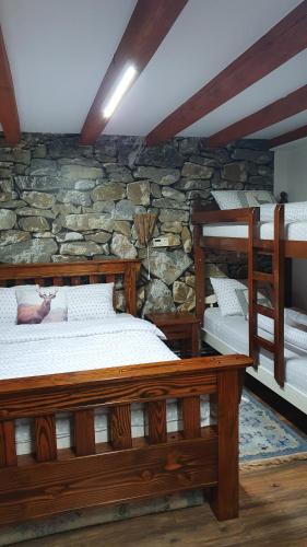 a bedroom with two beds and a stone wall at Vikendica Kločanica in Strmosten