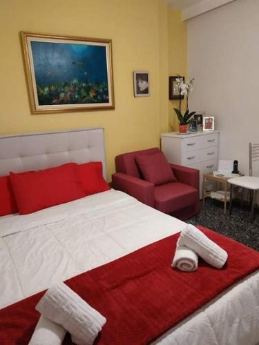 Schlafzimmer mit einem roten und weißen Bett und einem Stuhl in der Unterkunft 7th floor spacious veranda in the heart of Athens in Athen