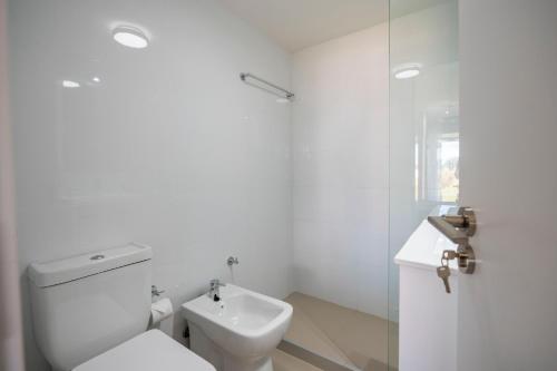 La salle de bains blanche est pourvue de toilettes et d'un lavabo. dans l'établissement SYRAH Premium B2 - Vistas al Parque by depptö, à Punta del Este