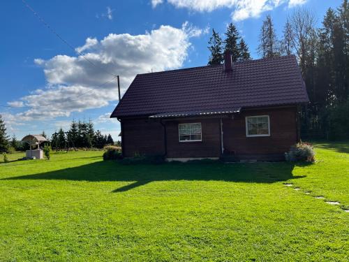 a small house in a field with a green yard at Rojaus kampelis. Kaimo turizmas in Gudžiūnai