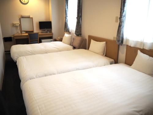 two beds in a hotel room with white sheets at Hotel Green Mark in Sendai