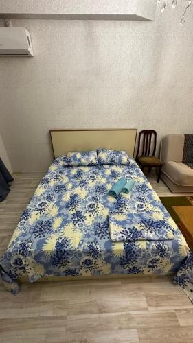 a bedroom with a bed with a blue and white bedspread at Однокомнатная квартира in Aktobe