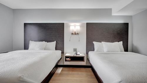 two beds sitting next to each other in a room at Days Inn & Suites by Wyndham Niagara Falls/Buffalo in Niagara Falls