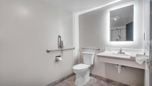 a white bathroom with a toilet and a sink at Days Inn & Suites by Wyndham Niagara Falls/Buffalo in Niagara Falls