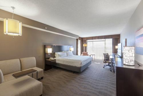 オースティンにあるHoliday Inn Austin Midtown, an IHG Hotelのベッドとリビングルームが備わるホテルルームです。