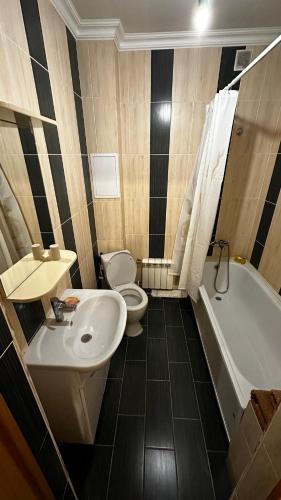 a bathroom with a sink and a toilet and a tub at Однокомнатная квартира in Aktobe