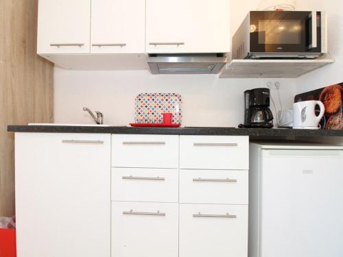 une cuisine avec des armoires blanches et un micro-ondes dans l'établissement Studio 2 places avec climatisation et wifi à Balaruc-les-Bains - FR-1-553-111, à Balaruc-les-Bains