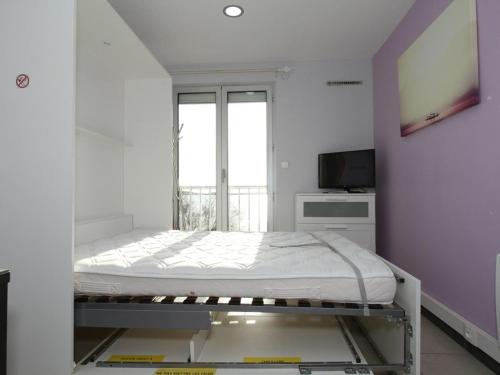 Cette chambre blanche dispose d'un lit et d'une télévision. dans l'établissement Studio climatisé avec WIFI à Balaruc-les-Bains - FR-1-553-23, à Balaruc-les-Bains