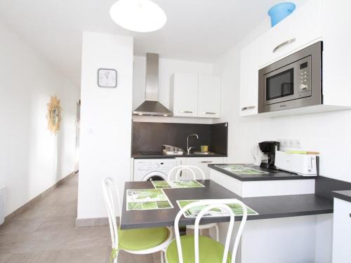 - une cuisine avec des placards blancs et des chaises vertes dans l'établissement T1 Rénové près des Thermes, Parking Privé, Balaruc-les-Bains - FR-1-553-125, à Balaruc-les-Bains